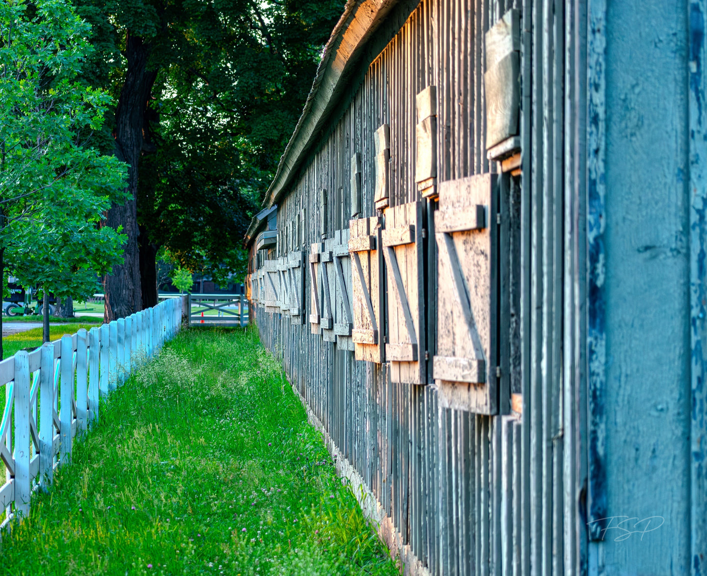 The side of a weathered stable is shaped by cool and warm light.